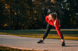 © Zoran Zeremski - Young woman warming up and stretching before running in park.