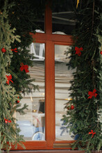 Stylish Christmas Spruce Branches With Red Bows Decoration On Window Of Building Or Shop. Christmas Festive Decor For Winter Holidays In European City Street. Merry Christmas!