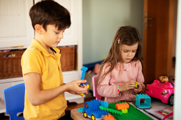 SIster and brother playing with toys at home. Little childs playing with lots of toys indoor.