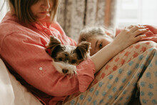 Woman With Dog And Daughter Sitting In Bedroom