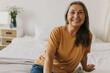 © shurkin_son - Sweet, adorable modern grandmother in casual T-shirt and jeans laughing sitting on bed chilling after home tasks, feeling joy and happiness, relaxing in bedroom while pie are being cooked in oven