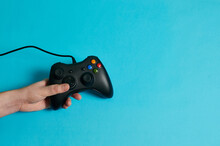 Hand Of A Man Holding A Video Console Controller On A Blue Background
