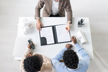 Wall Mural - Directly above view of African American couple sitting at table in bank office and drawing documents on credit