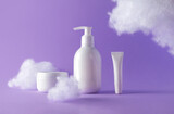 Fototapeta Mapy - Cosmetic set with fluffy clouds on violet background. Beauty products bottles for skincare or body care. Concept care with sensitive skin. Creative still-life photo