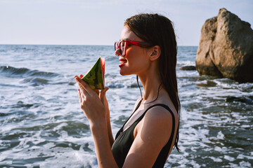 Wall Mural - woman in black swimsuit with watermelon by the ocean