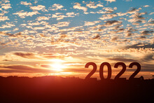 Concept Of New Year 2022. Silhouette Of Man Jumping From 2021 To 2022 With Cloud Sky Sunset Background.