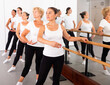 © JackF - Female ballet trainer teaching group of multiracial dancers near ballet barre in dancing hall