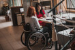 Two girls in wheelchairs in a cozy cafe waiting for an order. Accessible common areas for people with  special needs . Affordable tourism for people with special needs