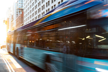 Wall Mural - New York City bus driving down the street through Manhattan with motion blur effect and sunlight background