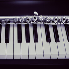 A Large Concert Transverse Flute Lies On The Piano Keys