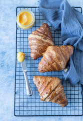 Wall Mural - French croissant. Freshly baked croissants with honey on blue concrete background.