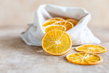 Wall Mural - Organic dried orange chips in eco canvas bag on light concrete background.