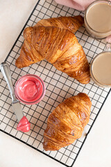 Wall Mural - Fresh crispy croissants with pink honey on black metal grille, concrete background. Top view.