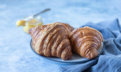 Wall Mural - French croissant. Freshly baked croissants with honey on blue concrete background.