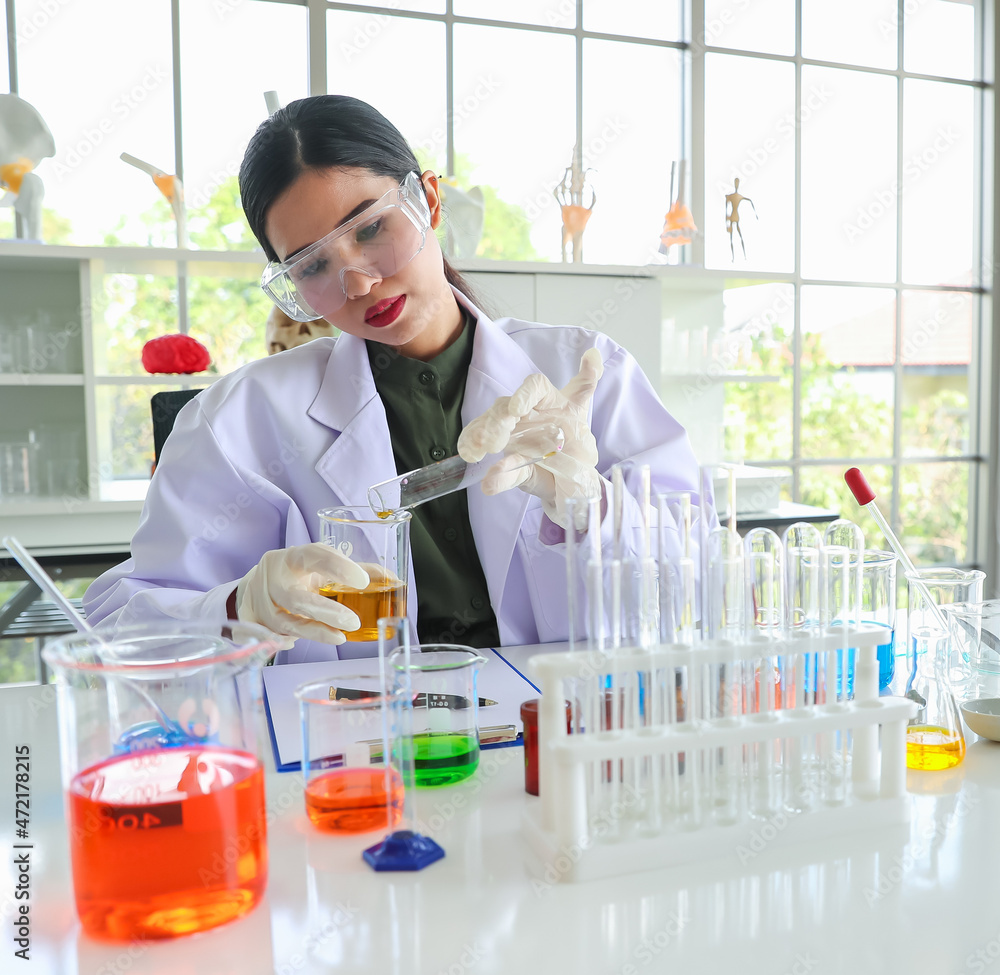 Asian woman as chemistry expert pouring experiment liquid from beaker ...