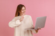 © khosrork - Portrait of positive attractive blond woman having video call, waving hand to camera, saying hello or good bye, wearing white sweater. Indoor studio shot isolated on pink background.