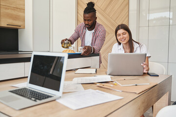 Wall Mural - Male with infuser teapot and busy female with laptop