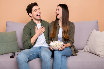 Photo of guy lady buddies sit comfy couch hold pop corn food bowl laugh comic show series isolated over beige color background