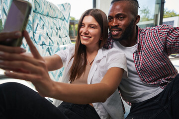 Wall Mural - Couple seated in room taking smartphone photos