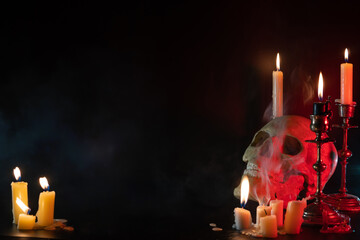 Skull head with candle lights set on black background. Old brass candlesticks. Smoke. The concept of mysticism and ritual. The religion of dark magic and Satanism. Mystical, terrible smoke of evil