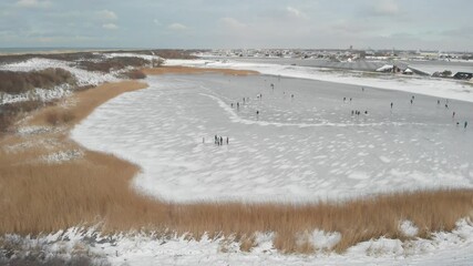 Wall Mural - people ice skating on a frozen lake during winter in the Netherlands