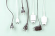 © vejaa - Many power cable cords with Eu plugs hanging over light green background. Electricity and energy efficiency concept. Front view