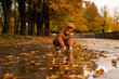 © VISTA by Westend61 - Girl wearing brown cap and raincoat crouching on road in park