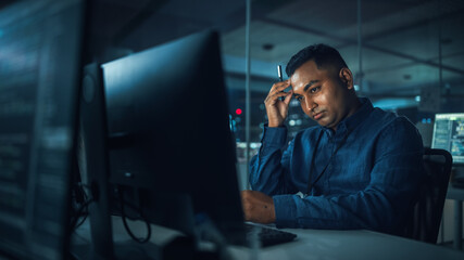 Poster - Night Office: Portrait of Handsome Indian Man in Working on Desktop Computer. Digital Entrepreneur Typing, Creating Software, e-Commerce App Design, Programming. Thoughtful Man Seeking Solution