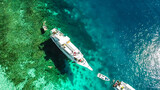 Fototapeta  - Top down drone shot of two boats anchored in one of the bays of Komodo National Park, Flores, Indonesia. The sea is crystal clear, shining with turquoise and blue shades. Island hoping