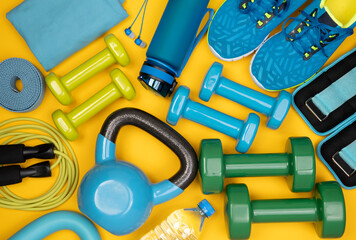 Wall Mural - Dumbbells, trainers, jumping rope and other fitness equipment on yellow background, top view