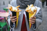 Fototapeta  - Belgian frites or french fries with mayonnaise in Brussels, Belgium. Female tourist holds two portions of fries in hands in the street.