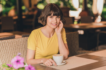 Wall Mural - Photo of dreamy charming young lady dressed yellow t-shirt sitting cafeteria drinking beverage smiling outdoors urban park