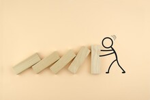 Falling Wooden Blocks, Drawn By A Person Holding Them. The Concept Of Strength, Leadership, Resistance. Wooden Cubes Fall Like Dominoes, Leaning On The Wall, Which Is Held By The Drawn Man.