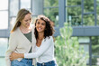 curly woman smiling while hugging girlfriend outside