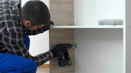 Wall Mural - A carpenter drilling holes in a kitchen shelf