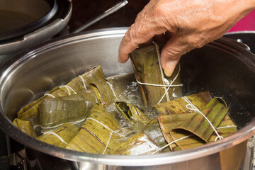 Wall Mural - Traditional Venezuelan cuisine for the December festivities, hands preparing Hallacas. Typical dish of ancient traditions where a mixture of ingredients are wrapped in banana leaves