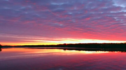Wall Mural - Perfect slow panning view of tranquil water reflecting sunrise with red clouds and colorful sky. This scenic yet generic view makes an excellent background for text or graphics too.