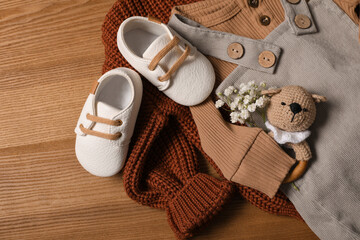 Wall Mural - Children's shoes, clothes and toy on wooden table, closeup