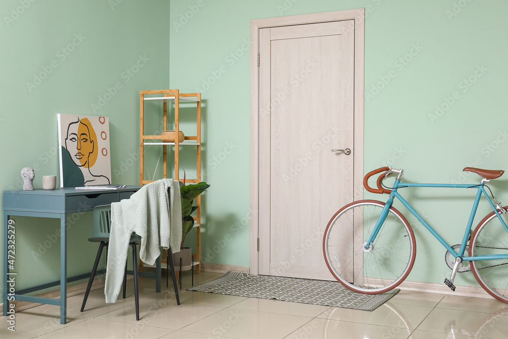 Interior of stylish room with modern workplace, shelving unit and bicycle