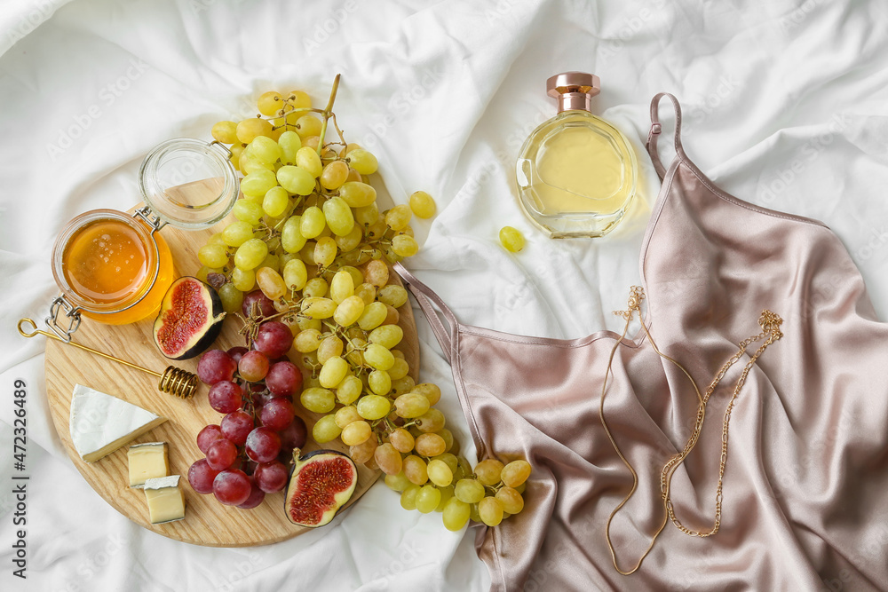 Composition with ripe grapes, fig, cheese and honey on light fabric background