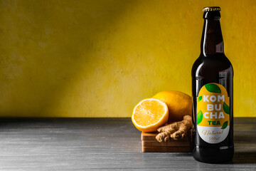 Bottle of natural kombucha with lemon and ginger on table