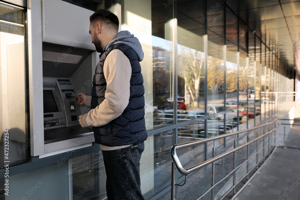 Young man using cash machine for money withdrawal outdoors Stock Photo ...