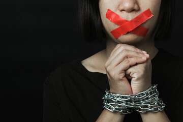 asian woman blindfold wrapping mouth with red adhesive tape and she was hand tethered on black backg