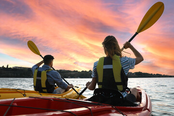 Wall Mural - Couple in life jackets kayaking on river, back view. Summer activity