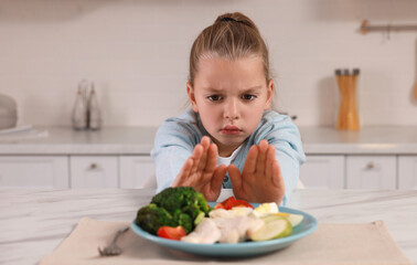 Poster - Cute little girl refusing to eat dinner in kitchen