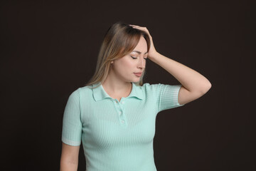 Wall Mural - Young woman suffering from headache on dark brown background