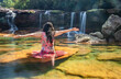 girl sitting on rock with waterfall flowing streams and blurred clear water long exposure shot