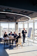 © DSMT - Confident businessman makes a presentation of a new project in the boardroom at a company meeting. Beautiful auditors talk with different partners about the business using a whiteboard and graphs.