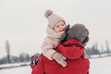 Canvas Print - Handsome bearded young dad and his little cute daughter are having fun outdoor in winter. Enjoying spending time together. Family concept