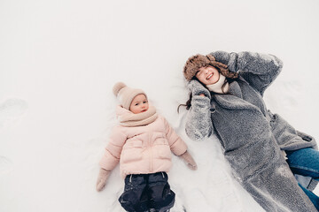 Canvas Print - Mom and daughter in winter. Happy family enjoy winter snowy day. They hug, laugh, have fun, ride in the snow and enjoy the winter snowy weather